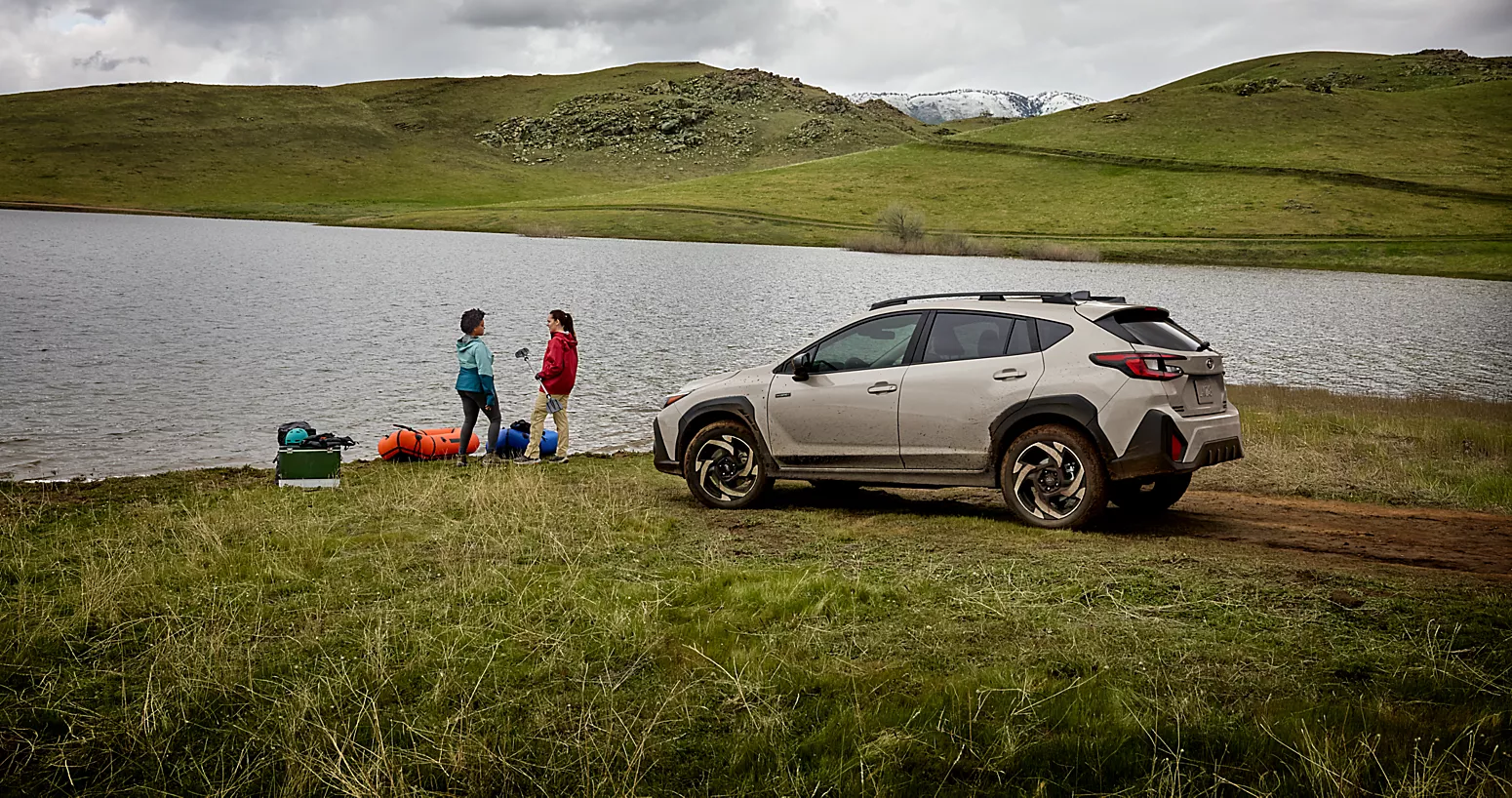 Subaru Crosstrek Hybrid parked by a lake with people camping nearby.