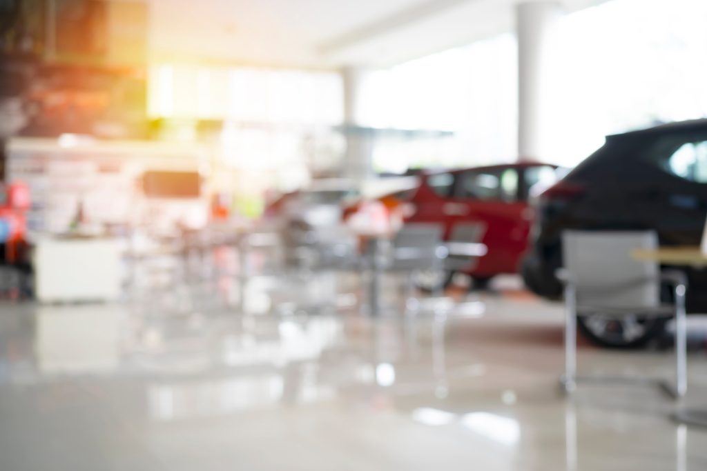 Blurred car showroom interior with vehicles on display.
